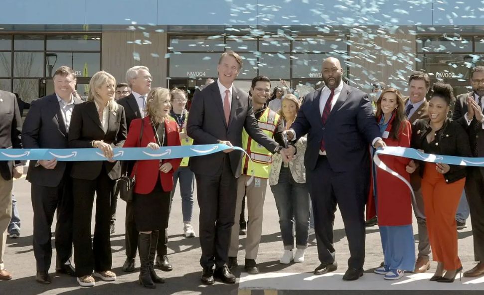 Governor Glenn Youngkin and local leaders cut a ceremonial ribbon at an Amazon facility opening, surrounded by partners and employees under celebratory confetti.